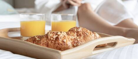 A breakfast tray with croissants and orange juice on a bed.