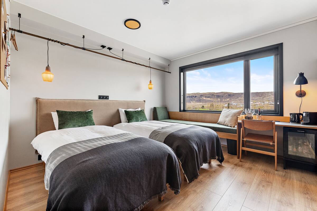 Une chambre avec deux lits, un bureau et une vue sur le paysage.