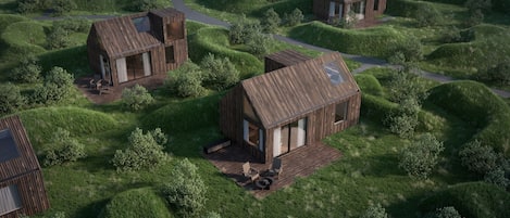 Una cabaña moderna de estilo rústico con terraza y zona de estar al aire libre, rodeada de exuberante vegetación.