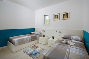 Ein Schlafzimmer mit zwei Betten, einem Fenster, einem Spiegel und zwei gerahmten Bildern an der Wand.