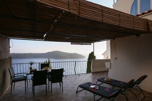 A balcony with a view of the sea, a table with chairs, and two sun loungers. - Apartment Amazing Summer (Dubrovnik)