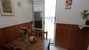 A dining area with a wooden table, chairs, a vase with flowers, and a bowl of fruit. - Apartment Amazing Summer (Dubrovnik)