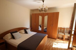 A bedroom with a large bed, wooden wardrobe, and a small table. - Apartment Amazing Summer (Dubrovnik)