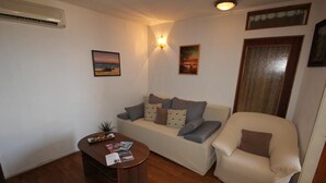 A living room with a sofa, armchair, and coffee table. There is a wall-mounted air conditioner and two wall-mounted lights. - Apartment Amazing Summer (Dubrovnik)