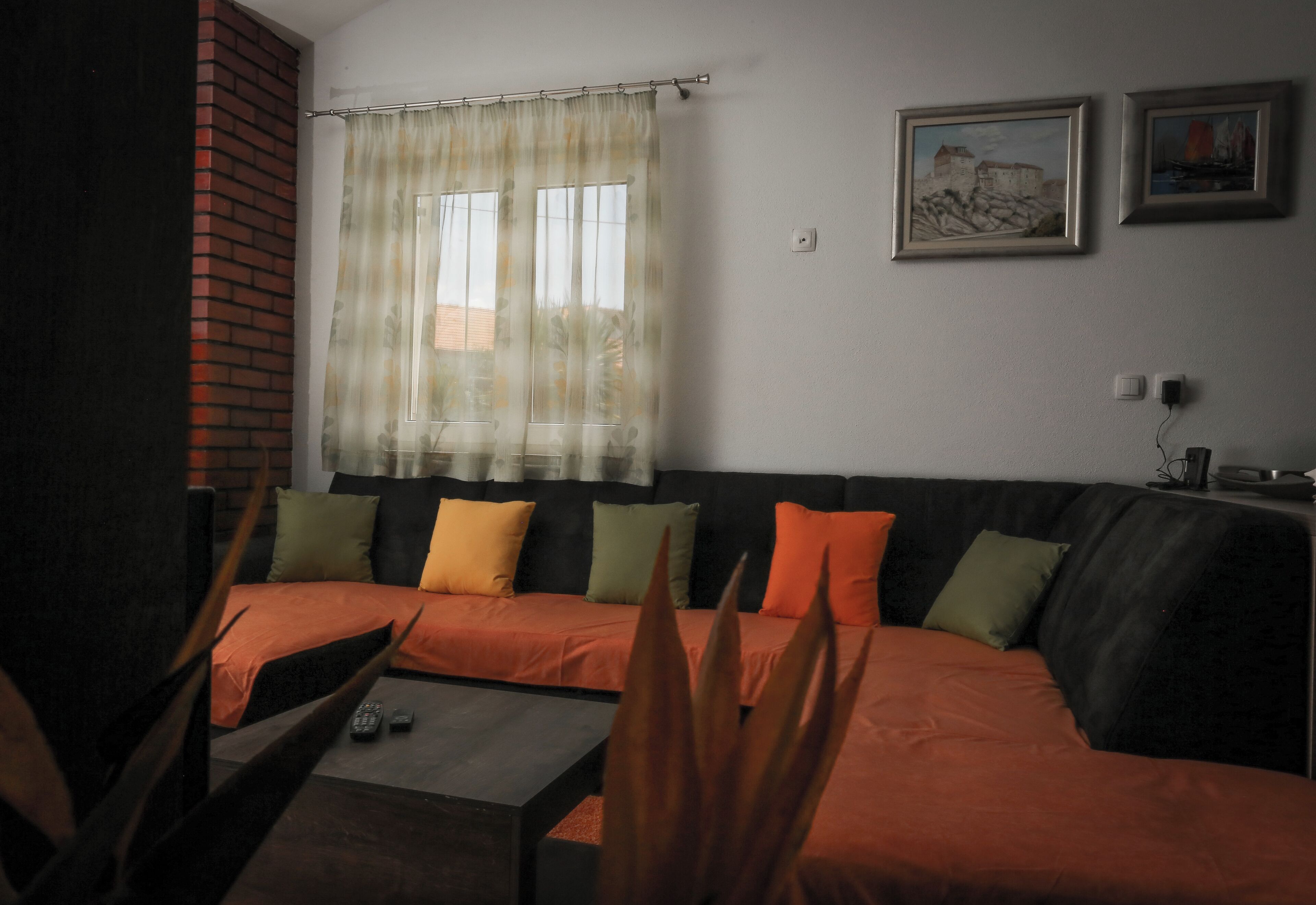 A living room with a sofa, a coffee table, and a window with curtains.