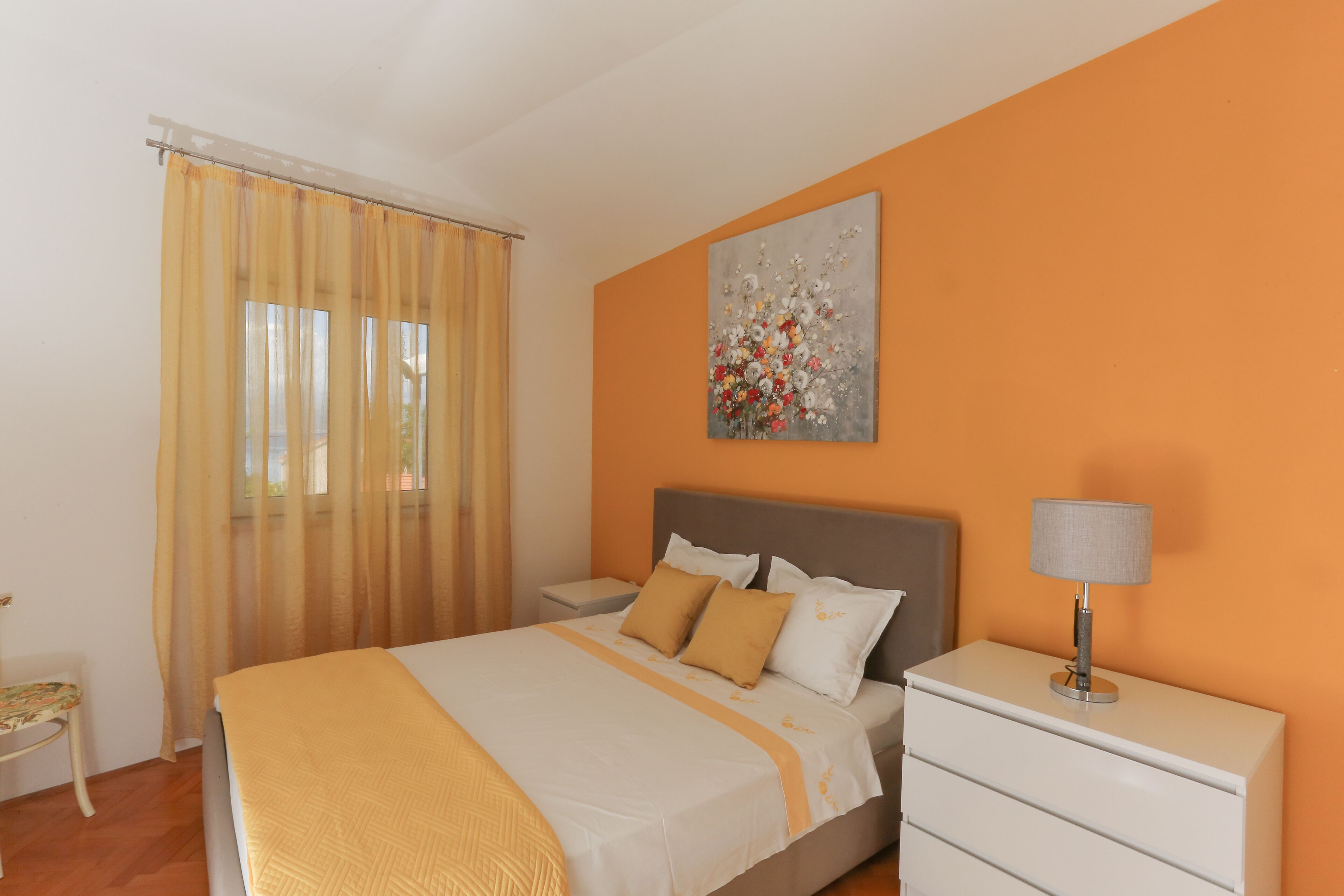 A bedroom with a bed, nightstand, and a painting on the wall.