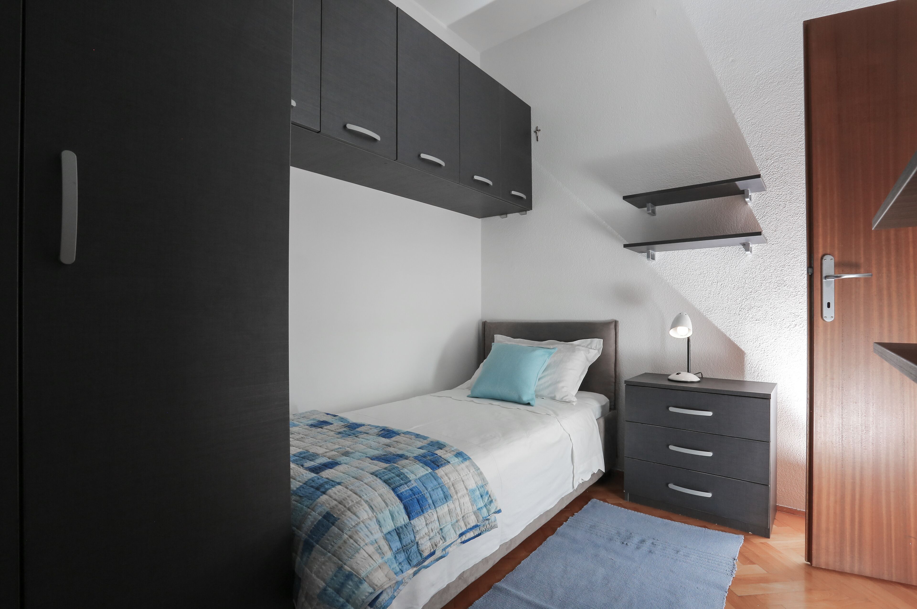 A bedroom with a bed, a nightstand, a dresser, and a wardrobe.