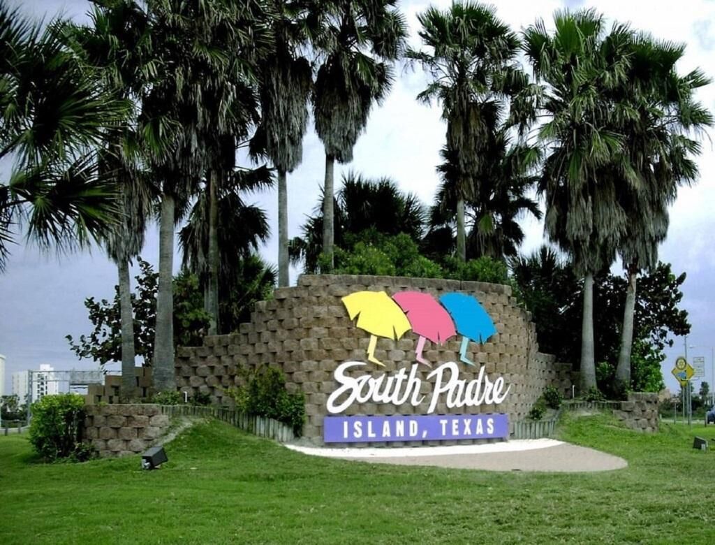 Un panneau indiquant l’île de South Padre, au Texas, entouré de palmiers.