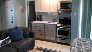 A compact living space with a kitchenette, a sofa with a patterned throw, and a dining area. - Studio on the beach! balcony ocean view, sleeps 4. pool, hot tub, BBQ. (South Padre Island)
