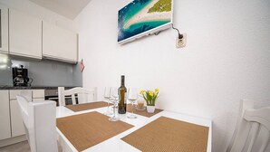 A dining area with a white table, brown placemats, and a bottle of wine. - Apartments Magdalena (Bol)
