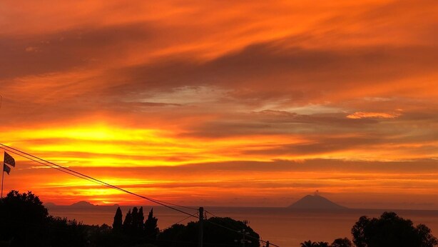 A sunset over a mountainous landscape with a flagpole in the foreground. - Bella Vista Apartaments N.6 (Tropea)