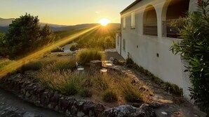 A house with a stone pathway leading to a seating area with chairs and a table. - Le Vignal 1, quiet cottage in the south of the Ardèche (Chambonas)