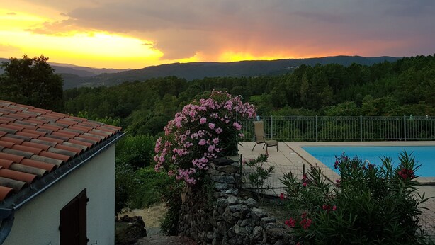 A pool area with a view of a sunset over a forested landscape. - Le Vignal 1, quiet cottage in the south of the Ardèche (Chambonas)