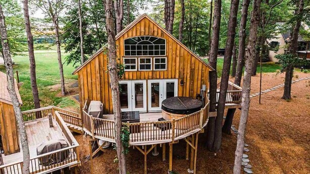 Una baita di legno con un balcone, immersa tra gli alberi.