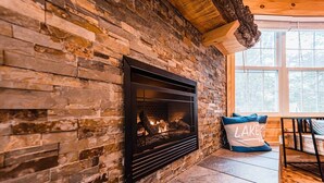 Una chimenea de piedra con fuego, una ventana y un banco con almohadones.