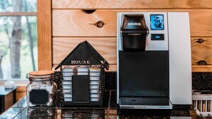 Una cafetera y un tarro de granos de café sobre una encimera de cocina.
