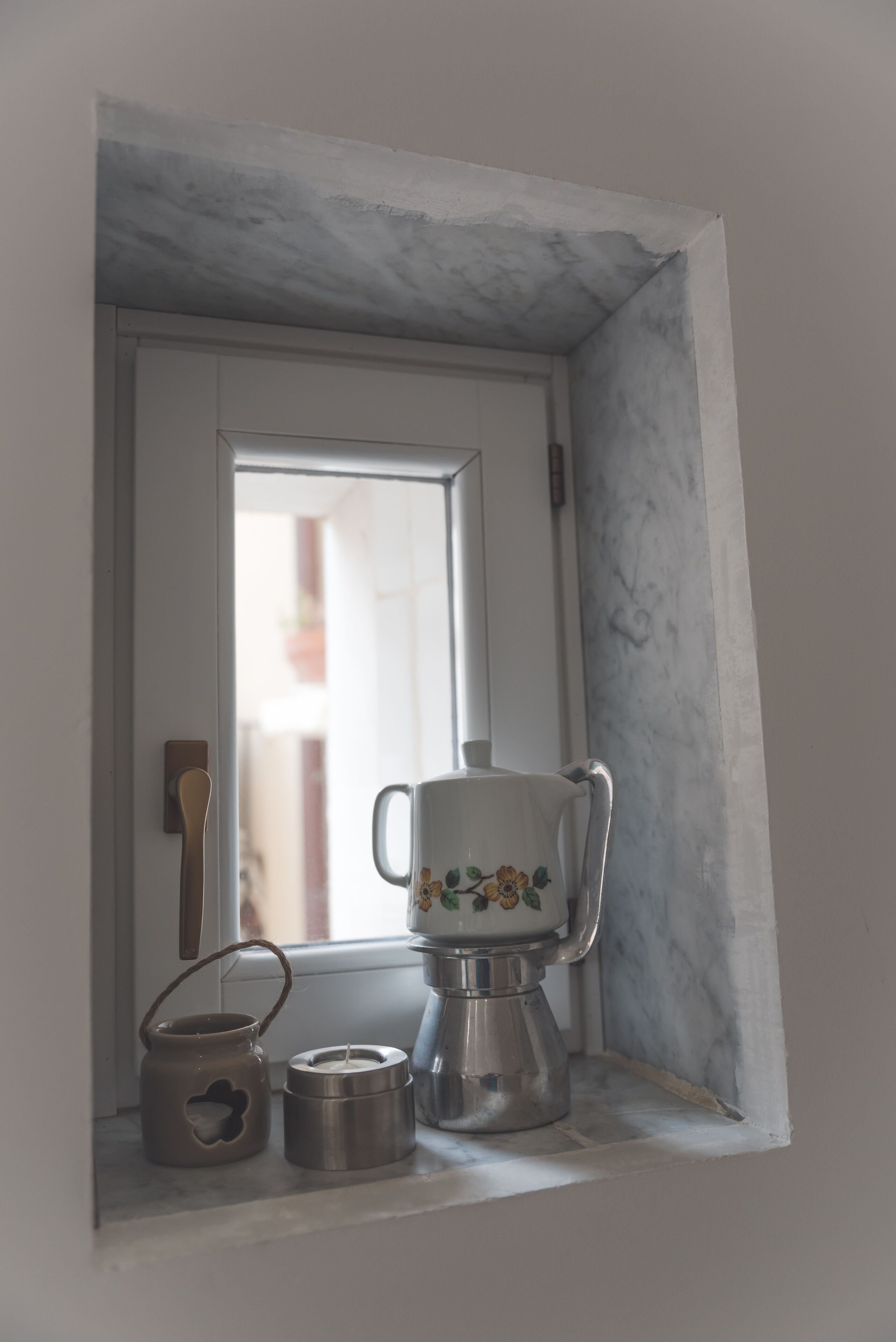 Un petit coin cuisine avec une fenêtre, une porte blanche et un mur en marbre.