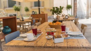 An outdoor café with wooden tables, chairs, and umbrellas. - Locanda LoSteri (Ragusa)