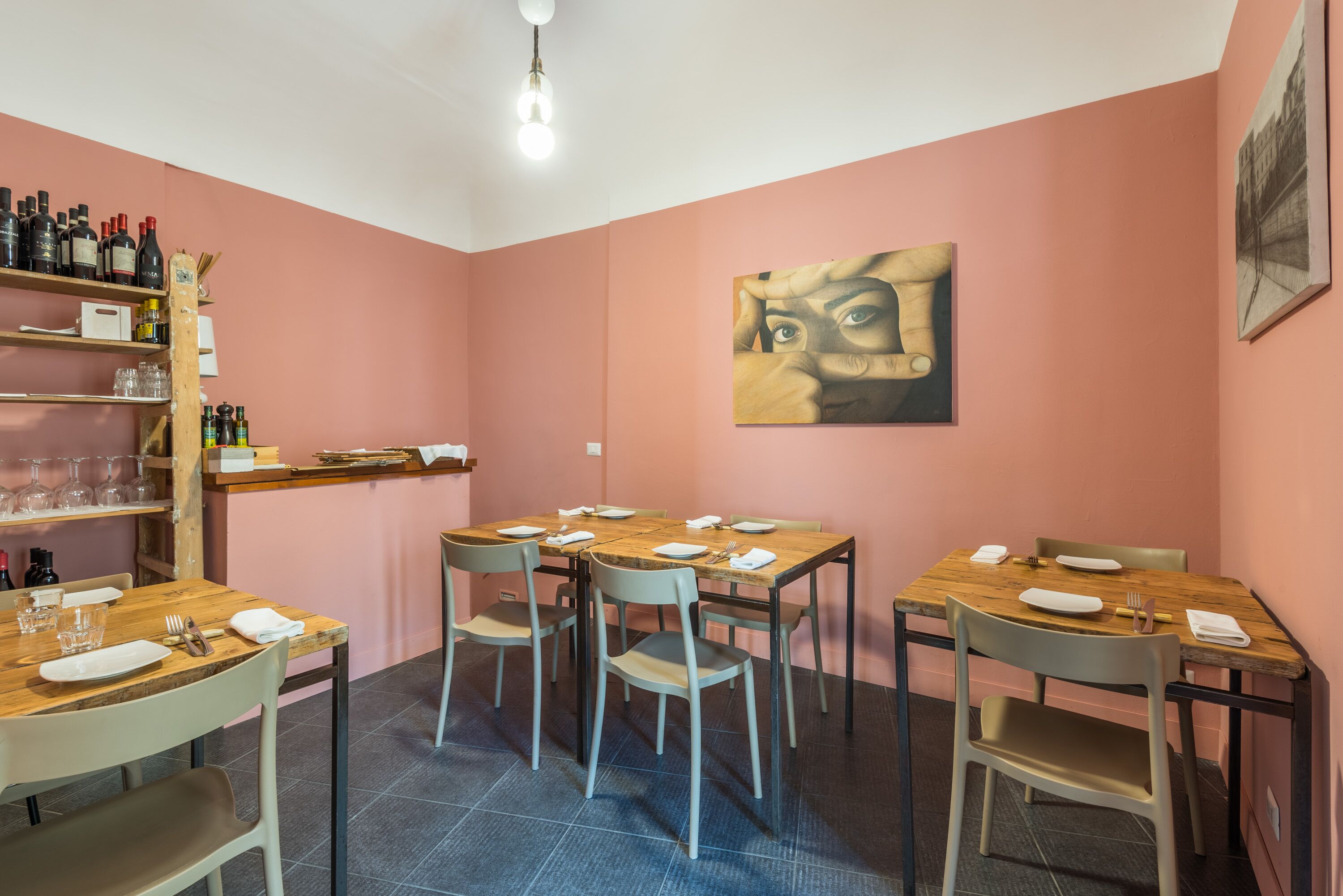 Ein Essbereich mit Holztischen und -stühlen, einem Weinregal mit Flaschen und einem Bild an der Wand.