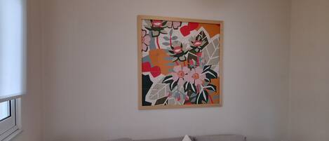 A living room with a grey sofa, two butterfly pillows, and a colorful abstract painting on the wall.