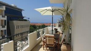 A balcony with a table, chairs, and an umbrella. - ChaniaStay Central Apartments (Chania)