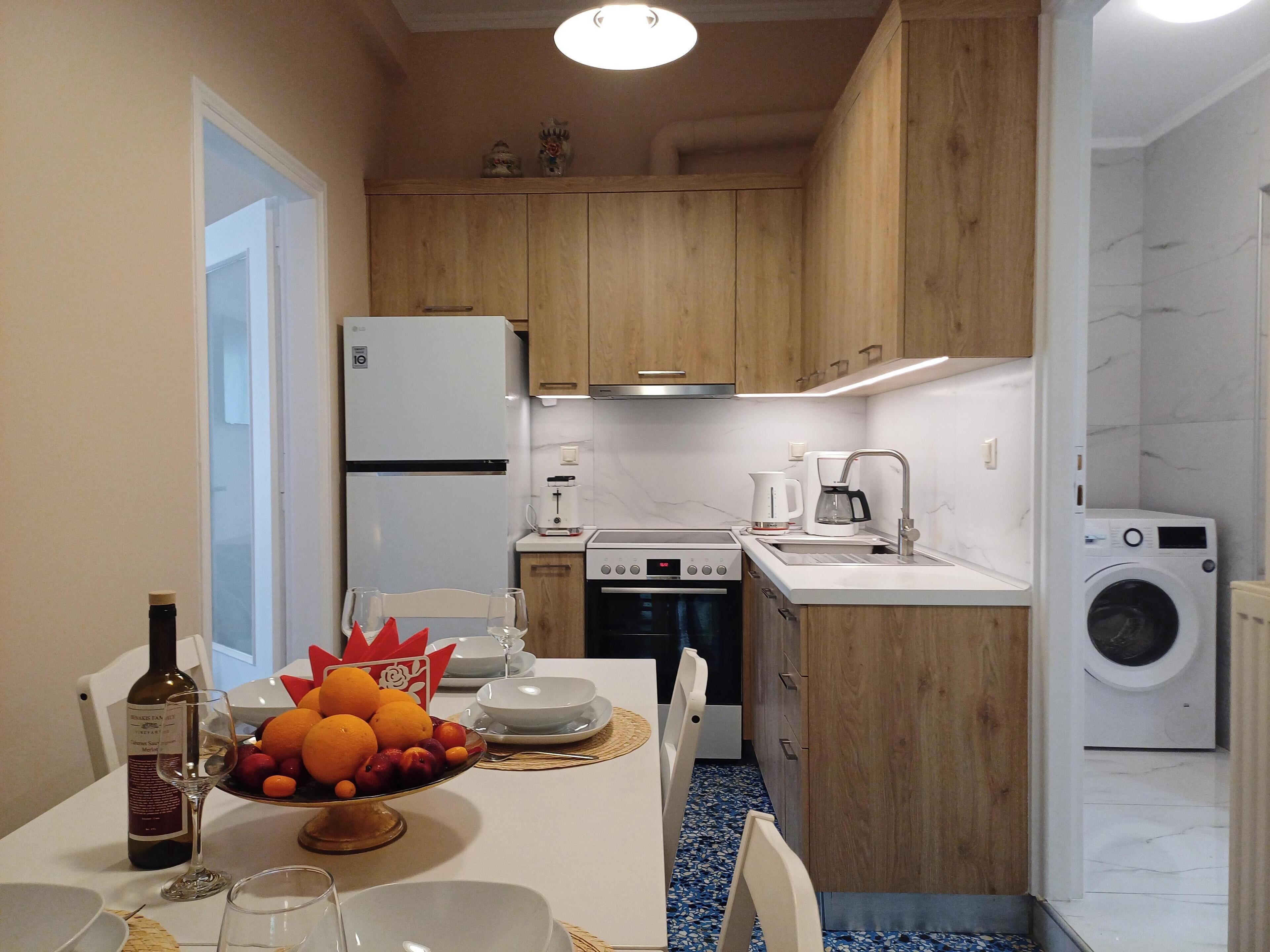 Une cuisine compacte avec des meubles en bois, un réfrigérateur blanc, une cuisinière, un évier et un lave-linge.