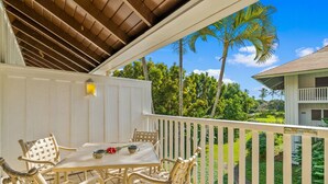 A covered outdoor area with a table and chairs, a white fence, and a view of a green landscape with trees. - Beautiful Poipu 1Br Condo with AC KP237 (Koloa)