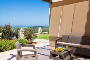 A balcony with wicker furniture, a table with fruit, and a view of the sea.
