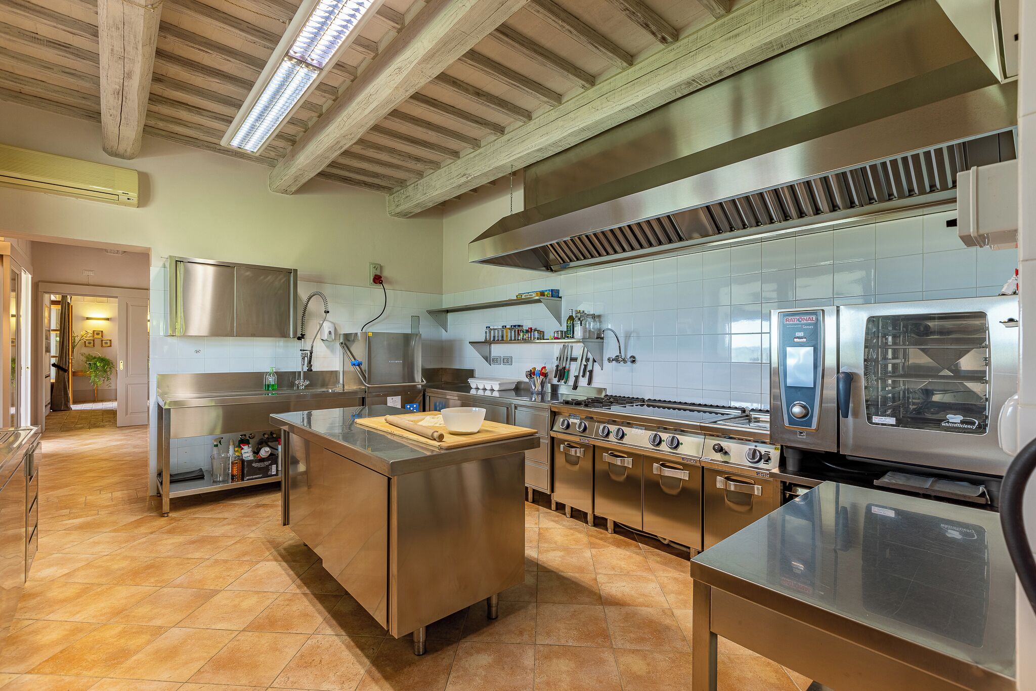 Cozinha moderna com eletrodomésticos de aço inoxidável, uma ilha central e painel de azulejos.