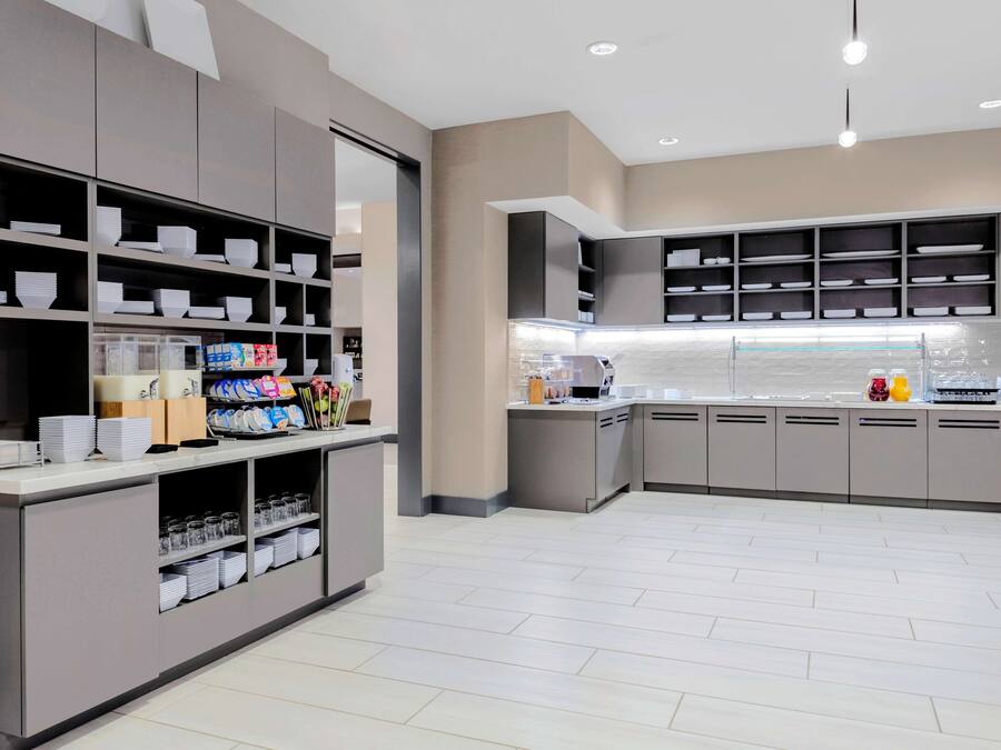 Uma cozinha moderna com prateleiras embutidas, uma ilha central e um painel de proteção atrás da bancada.