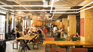 A spacious indoor dining area with high ceilings, exposed ductwork, and modern pendant lighting. - Jo&Joe Paris Nation - Hostel (Paris)