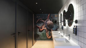 A modern bathroom with a mural of an octopus, white sinks, and mirrors. - Jo&Joe Paris Nation - Hostel (Paris)