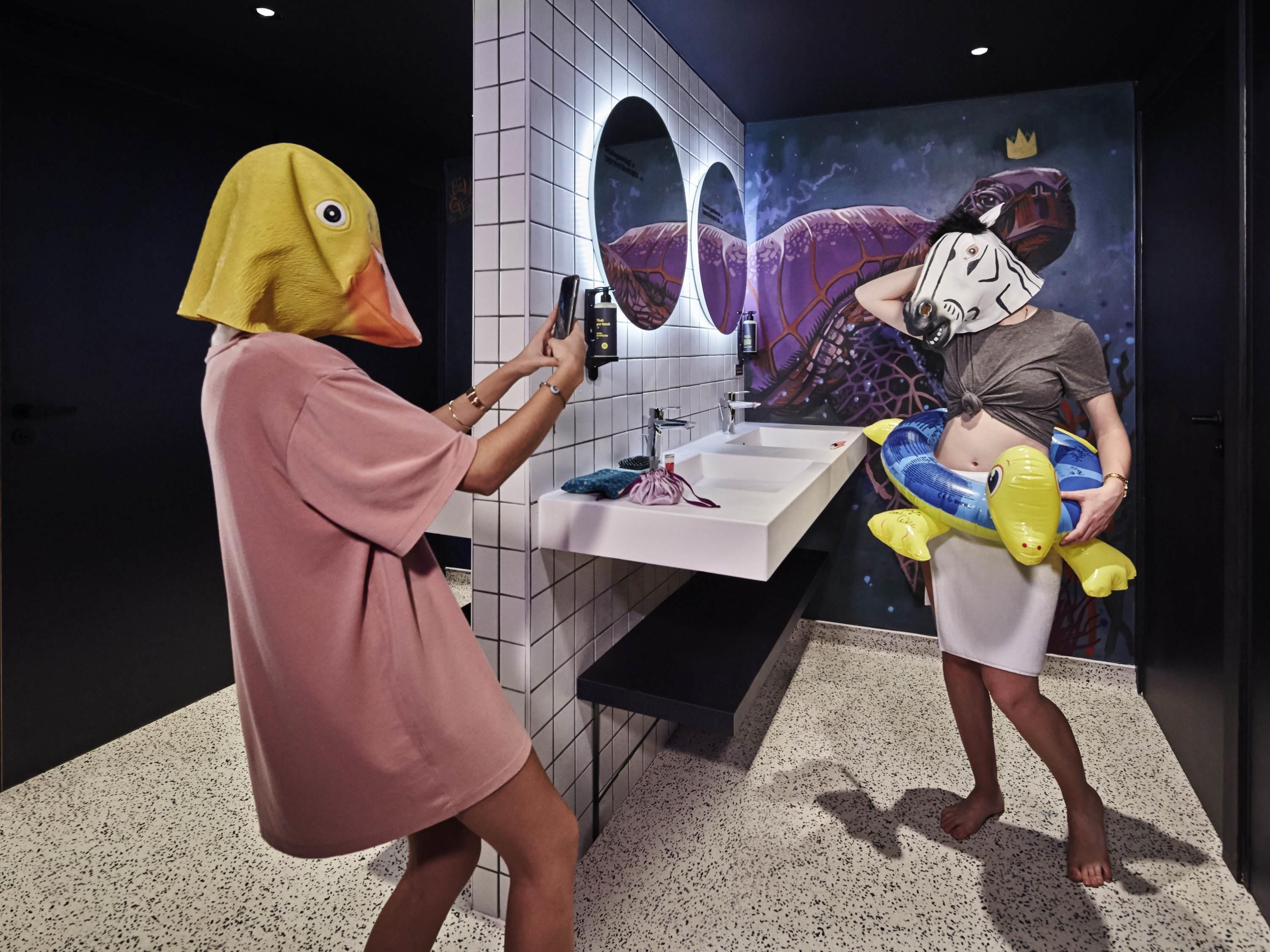 A bathroom with a white sink, a mirror, and a wall with a decorative mural.