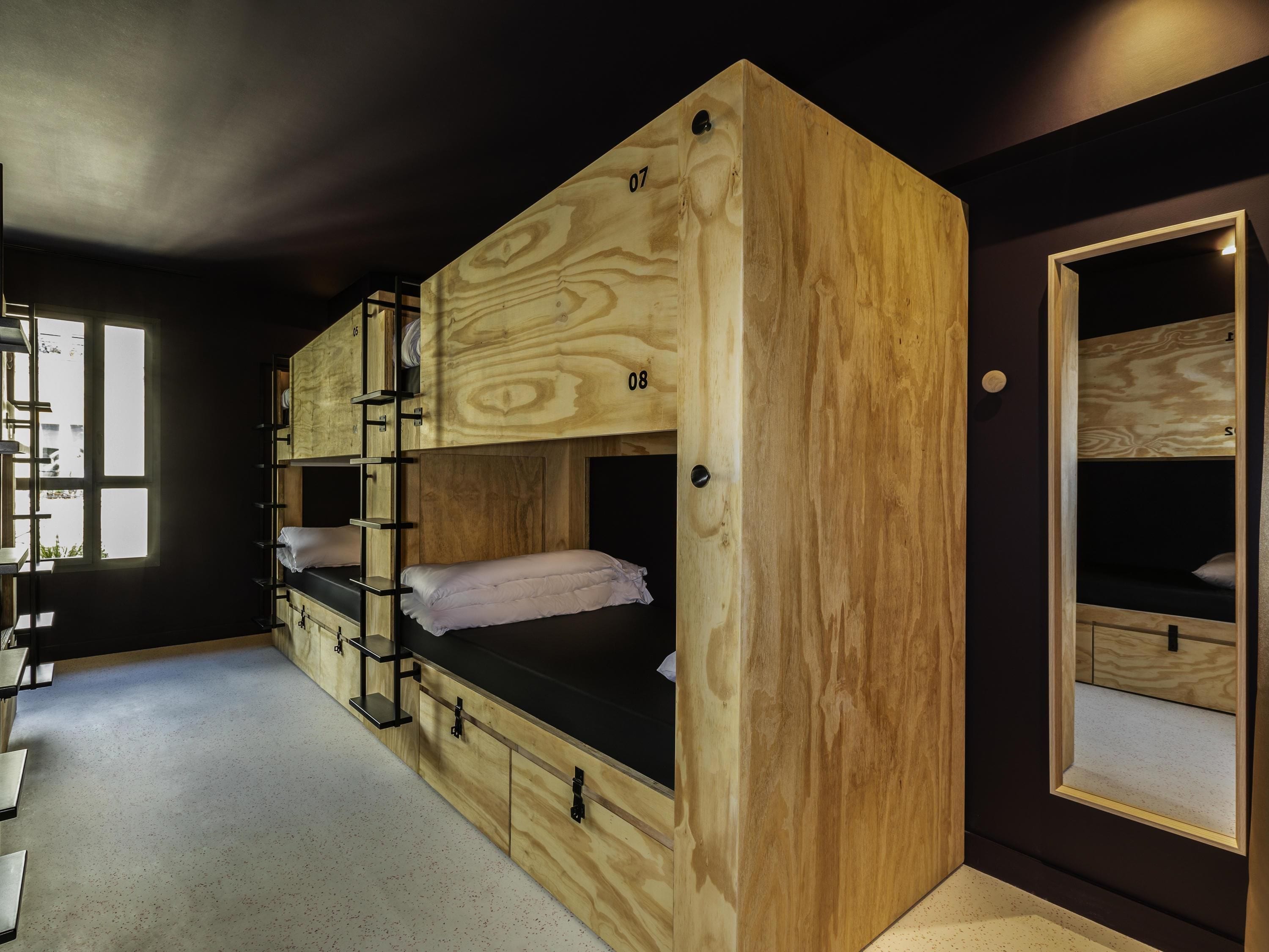 A bunk bed with a wooden exterior, a window with a view, and a door with a mirror.