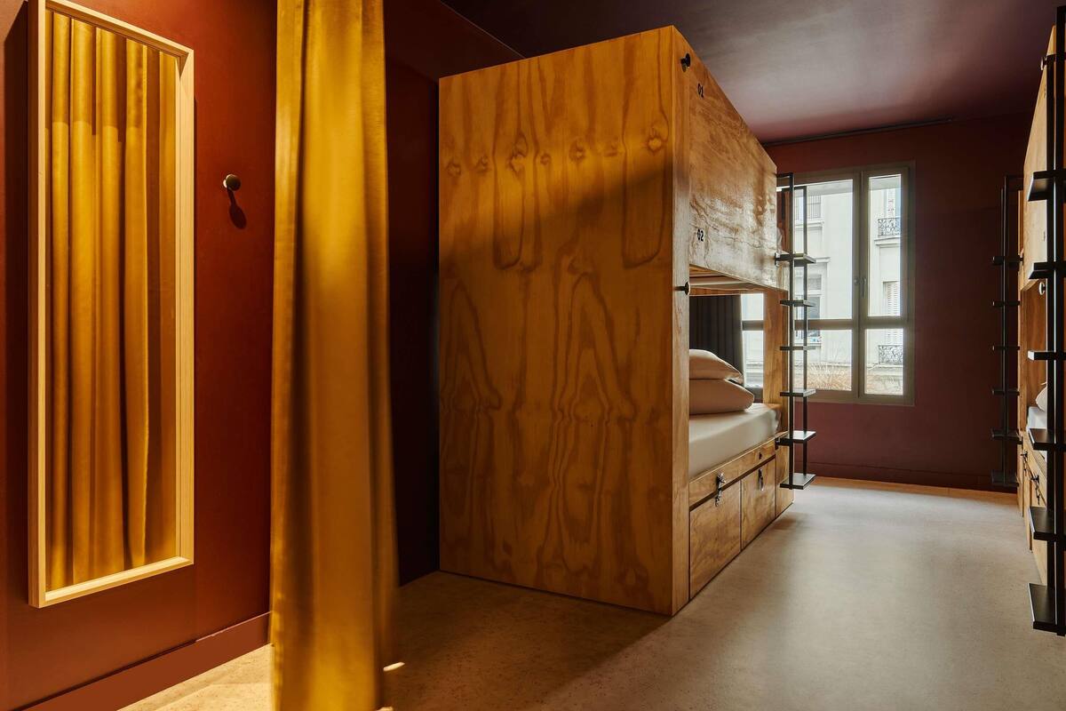 A compact room with a bunk bed, a wardrobe, and a window providing natural light.