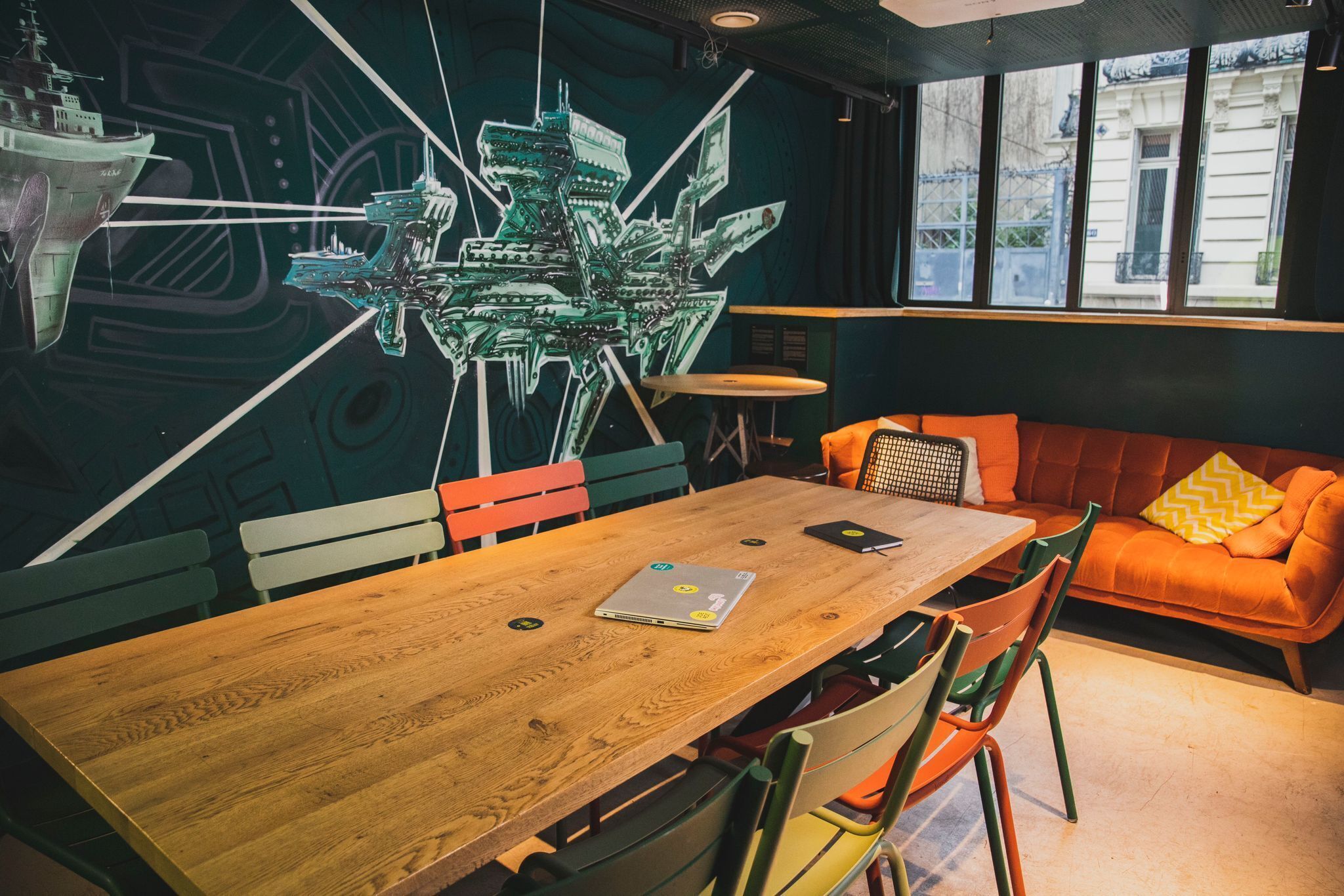 Un intérieur moderne avec une table en bois, des chaises colorées et un canapé orange vif.