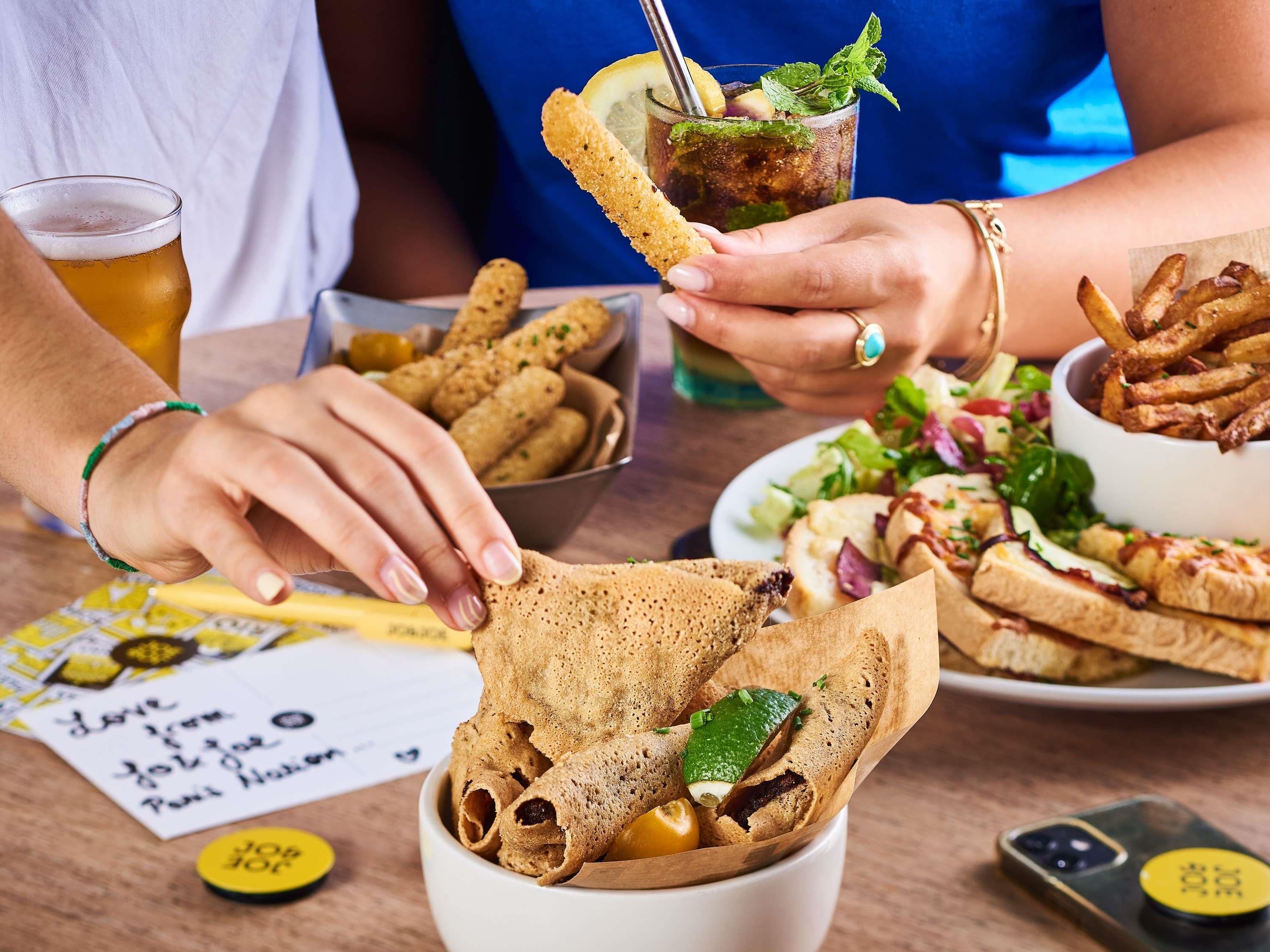 A dining table with food items, a drink, and a mobile phone.