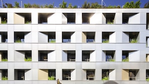A modern building with a flat facade, multiple balconies with greenery, and a ground-level restaurant. - Jo&Joe Paris Nation - Hostel (Paris)