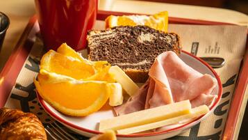 A tray with food items including bread, cheese, ham, orange slices, and a croissant.