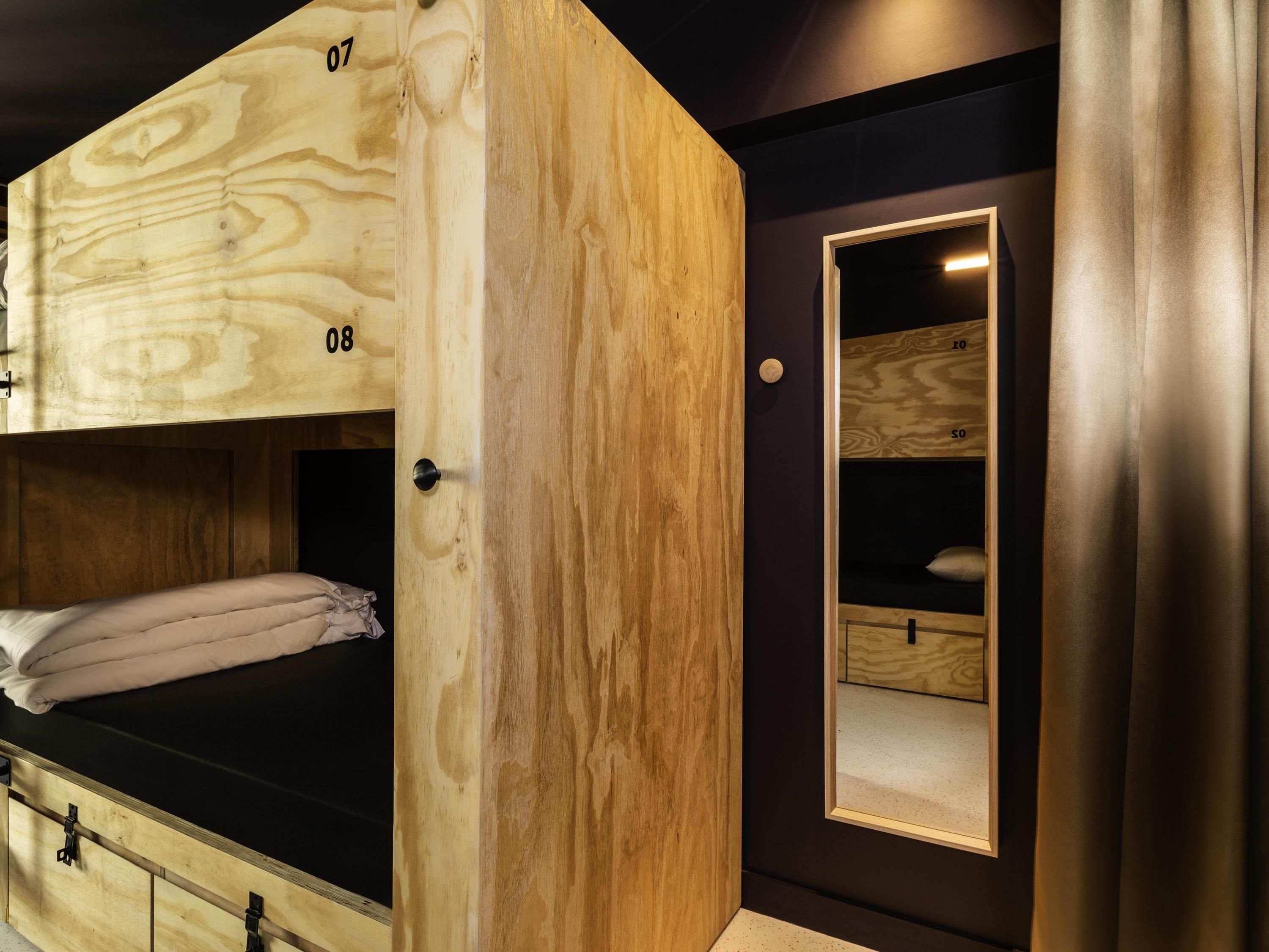 A wooden bunk bed with a built-in wardrobe and a mirror.