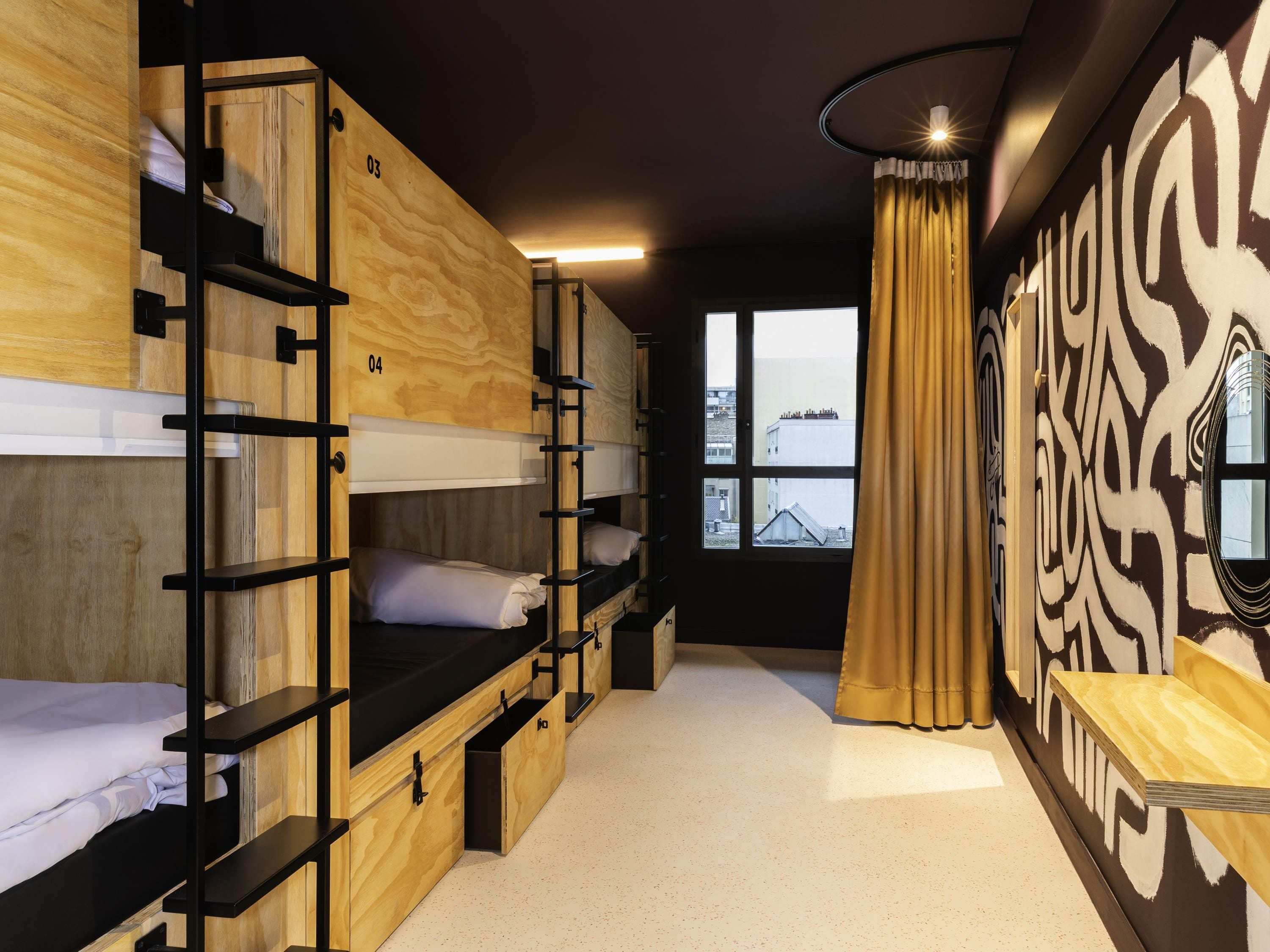 A room with bunk beds, a window with a view, and a patterned wall.