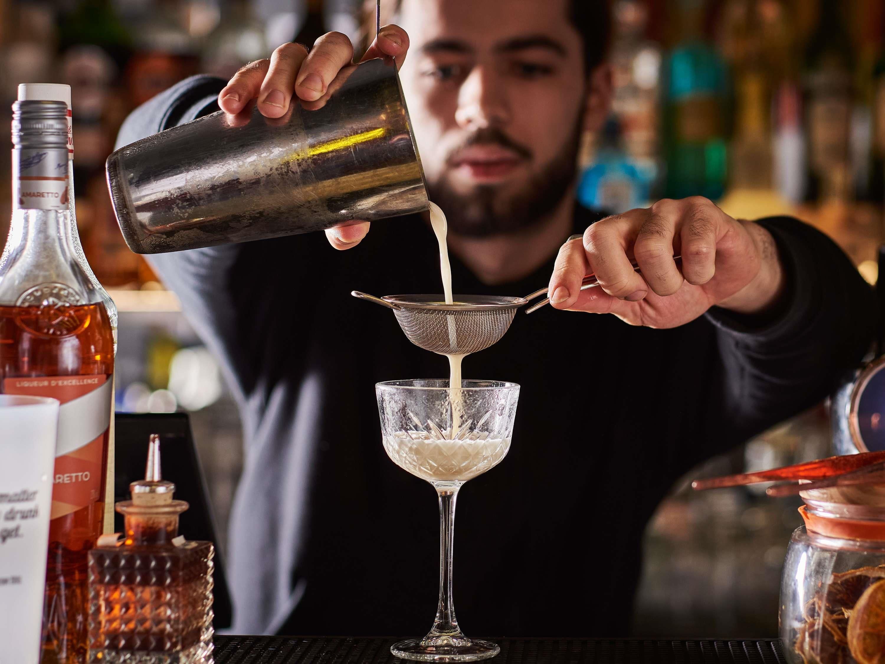 Un cantinero sirviendo una bebida en un vaso.
