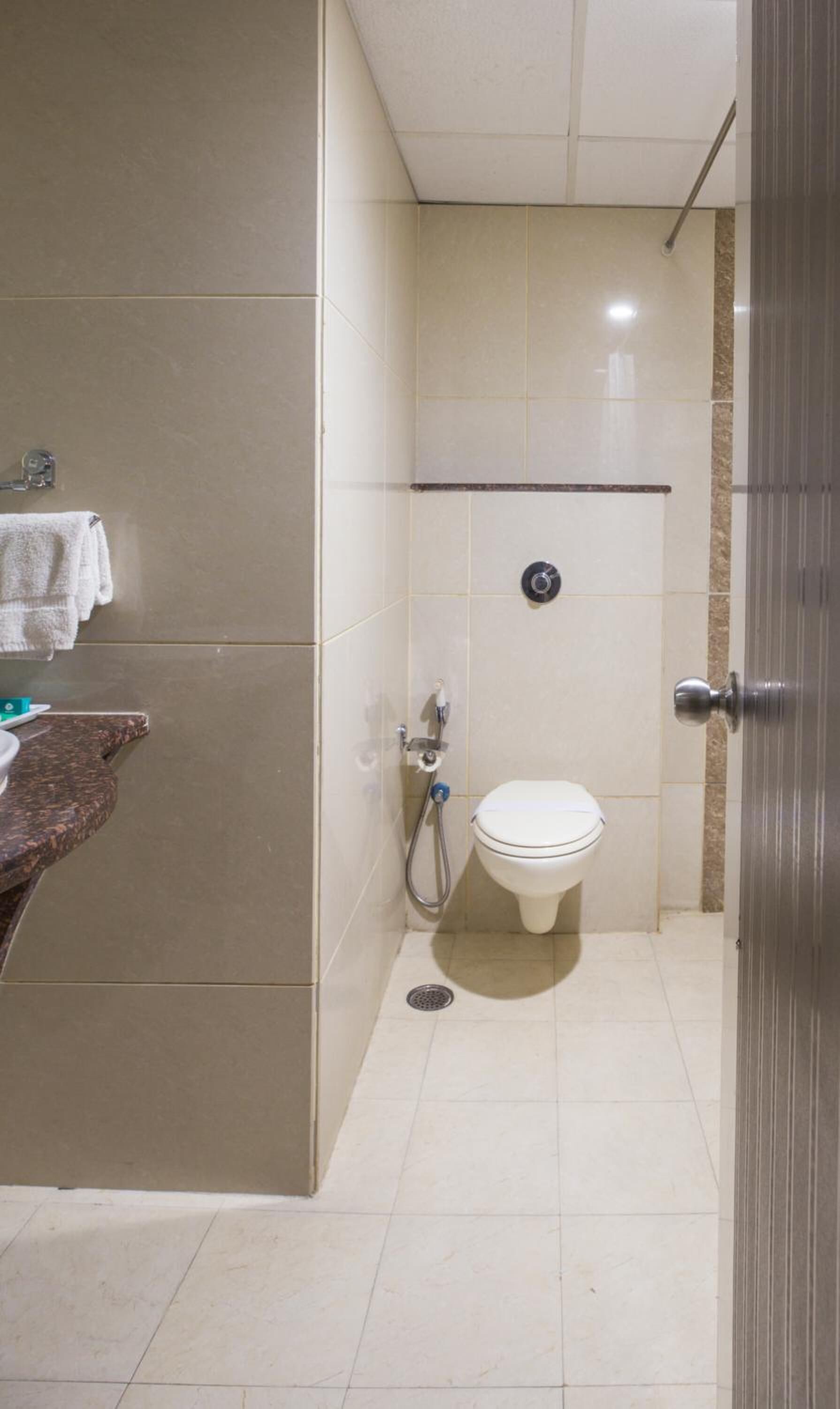 Une salle de bain équipée de toilettes, d’une douche et d’un porte-serviettes.