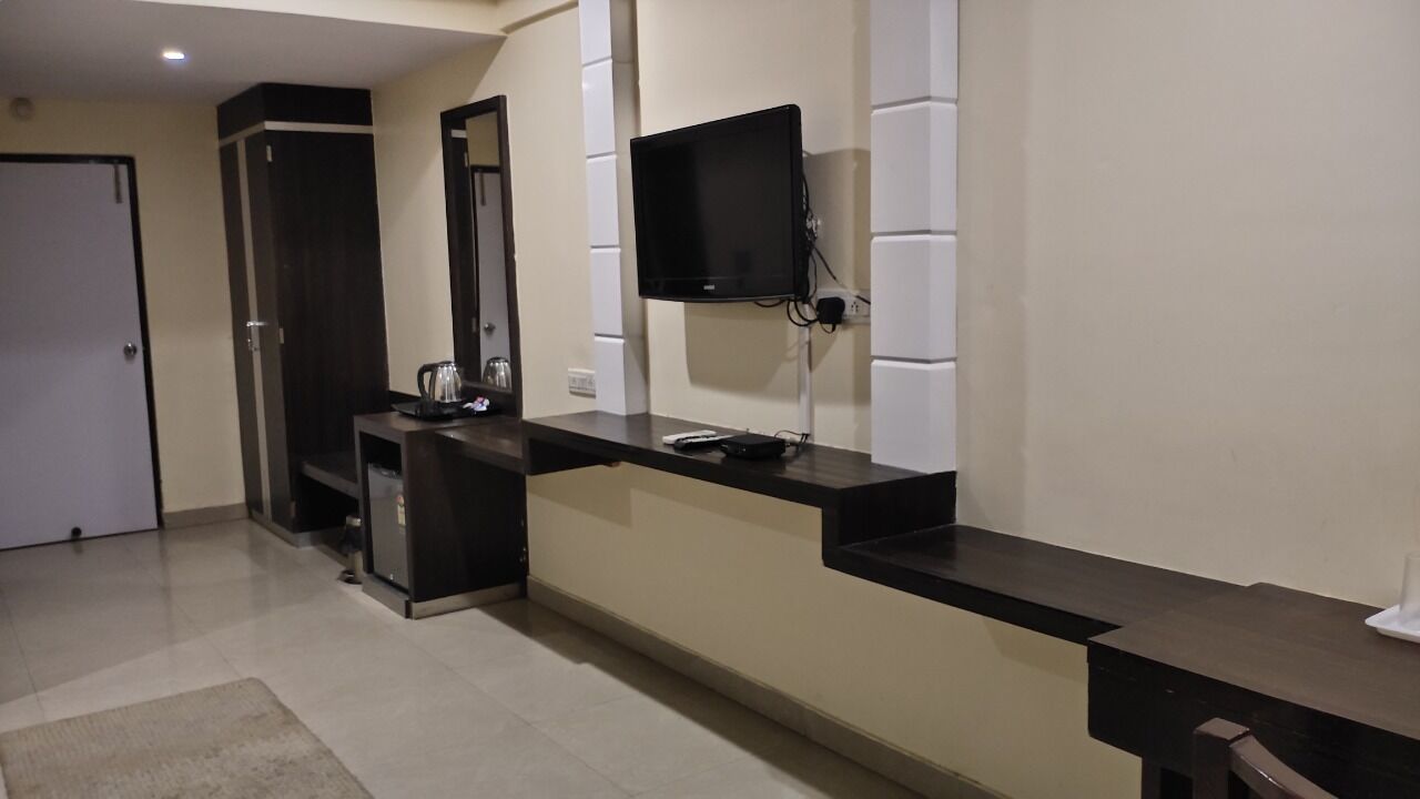 A modern kitchen with a built-in TV, a coffee machine, and a small refrigerator.
