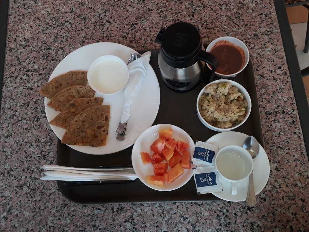 Un plateau contenant divers aliments, notamment des galettes, un saladier de fruits, une tasse de thé et un bol de soupe.