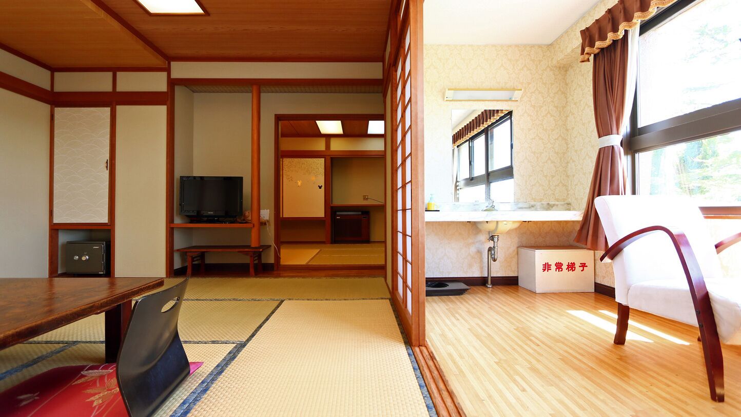 Una habitación tradicional japonesa con suelo de tatami, televisor, escritorio y ventana con cortinas.