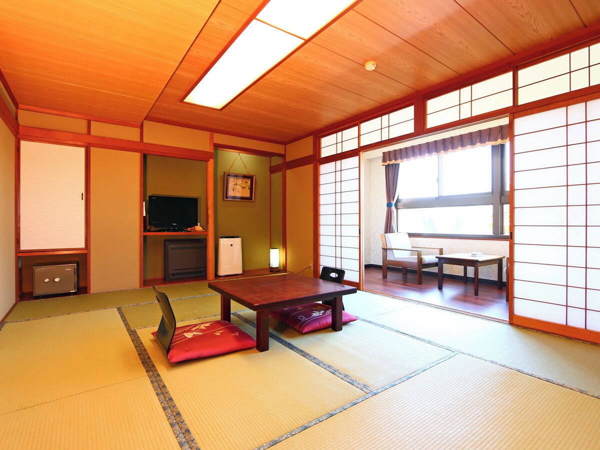 Una habitación tradicional japonesa con suelo de tatami, una mesa baja y puertas correderas.