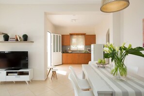 Una cocina moderna con armarios de madera, un refrigerador blanco y una zona de comedor con una mesa y sillas a rayas.
