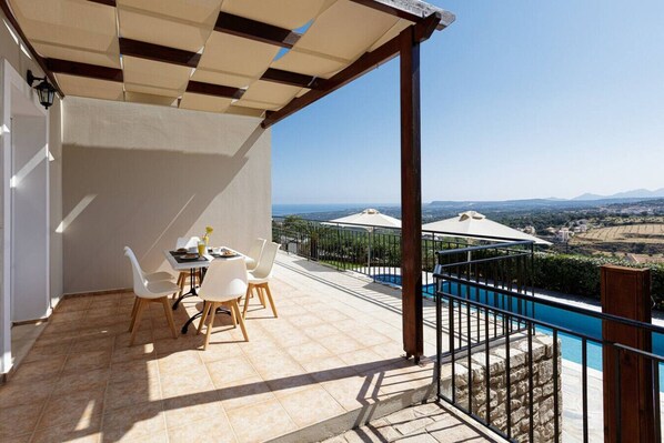 Una terraza con mesa y sillas, una piscina y vistas al paisaje.