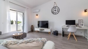 Een moderne woonkamer met een televisie, bureau en een groot raam.